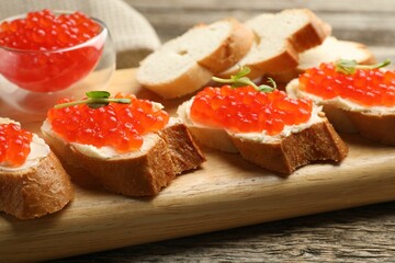 Sandwiches with red caviar and microgreens on wooden table, closeup