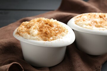 Delicious rice pudding with cinnamon in bowls on table, closeup
