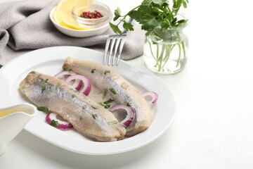 Tasty herring fillets with onions and parsley served on white table, closeup