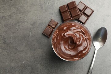 Tasty pudding and pieces of chocolate on grey table, flat lay. Space for text