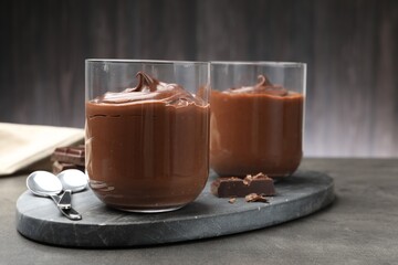 Tasty pudding and pieces of chocolate on grey table, closeup