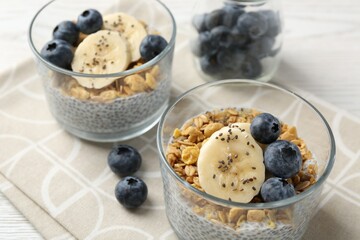 Delicious dessert with chia seeds, yogurt, granola, blueberries and banana on table, closeup. Superfood