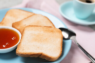 Slices of tasty toasted bread, jam and spoon on pink tablecloth, closeup