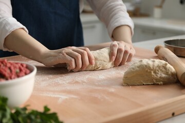 Making khinkali. Woman kneading dough at table in kitchen, closeup