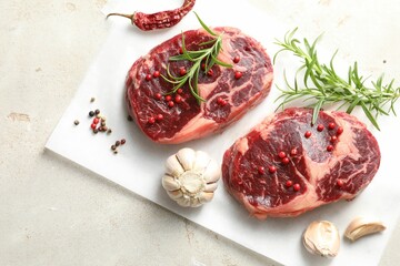 Pieces of raw beef meat and spices on gray textured table, flat lay