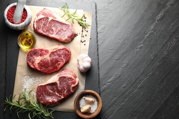 Pieces of raw beef meat and spices on black table, flat lay. Space for text