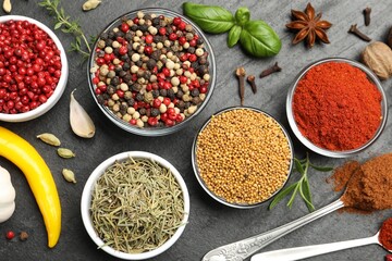 Different aromatic spices on black table, flat lay