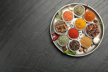 Different aromatic spices on black table, top view. Space for text