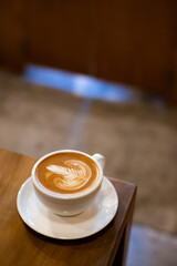 A beautifully crafted latte with intricate foam art on a wooden table.
