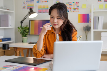 Woman immersed in design thinking, reviewing her work on a laptop in a bright, organized studio...