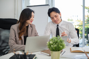 Business colleagues discussing ideas and reviewing content on a digital tablet and laptop during a strategy meeting.