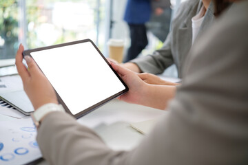 Close up of businesswoman holding digital tablet with a blank screen during a business meeting.