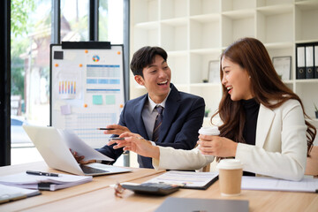 Young professional man and woman having an engaging discussion over documents and charts in a bright modern office.
