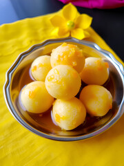 Boondi sweet plated in silver bowl, sugar syrup soaked pearls, bright yellow and orange hues, styled with