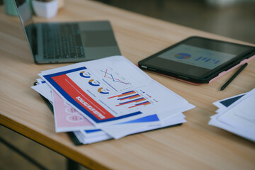Businesswomen are having a meeting, discussing and analyzing charts and graphs, using a pen to...