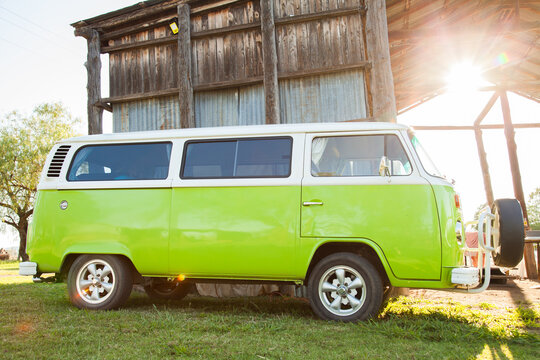 Sun flare over retro green mini bus van on farm