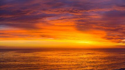 Fototapeta premium Vivid Orange and Purple Sunset Over the Ocean