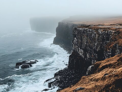 A misty coastal scene with steep cliffs and rough seas.
