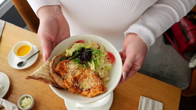 Woman holding a plate of caesar salad