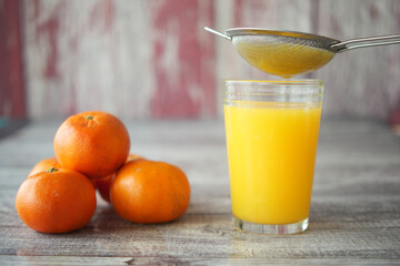 Freshly squeezed orange juice being strained into a glass