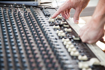 Sound guy turning knobs on a sound system audio mixer