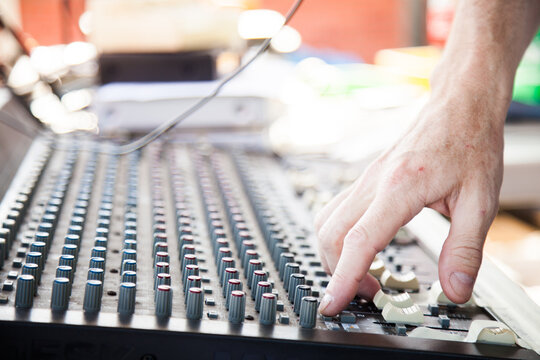 Hand adjusting knobs on a sound system audio mixer