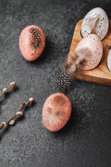 Set of Easter eggs with feathers in wooden holder. Rustic spring composition for festive decoration.