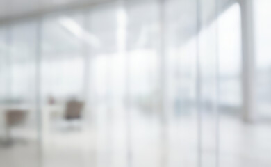 Blurred office interior with glass walls and furniture in a bright environment.
