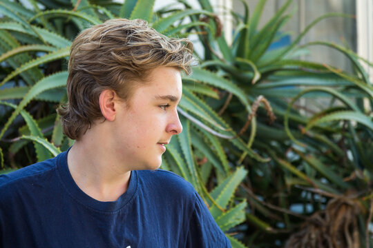 Teenage boy in profile in front of cactus plant