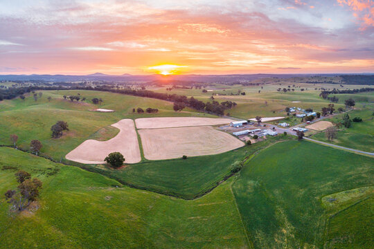 Aerial view of ploughed paddocks near farm buildings at sunset