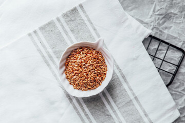 Natural flaxseed in a small bowl on a kitchen towel