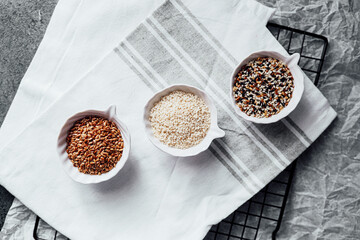 Different seeds displayed in small bowls on a kitchen towel during meal prep