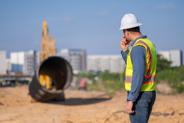 Engineer worker operations construction plans large black drainage pipe installing underground...