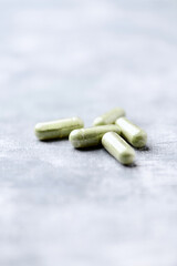 Barley grass capsules. Antioxidants. Concept for a healthy dietary supplementation. Bright background. Soft focus. Close up. Copy space.	
