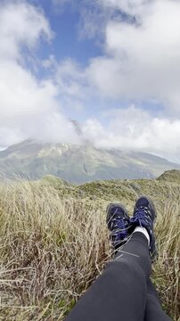 Point of view of hiking boots with powerful Mount Taranaki in background, along the picturesque Pouakai Summit Trail in Egmont National Park. Spectacular hiking trails on New Zealand North Island
