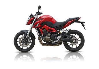 Obraz premium Side view of a red and black motorcycle on a white background with a slight reflection below it