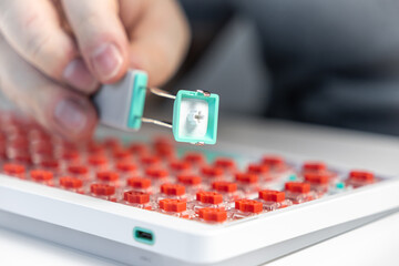Close-up of keycap puller tool removing teal key from red switch mechanical keyboard for modding