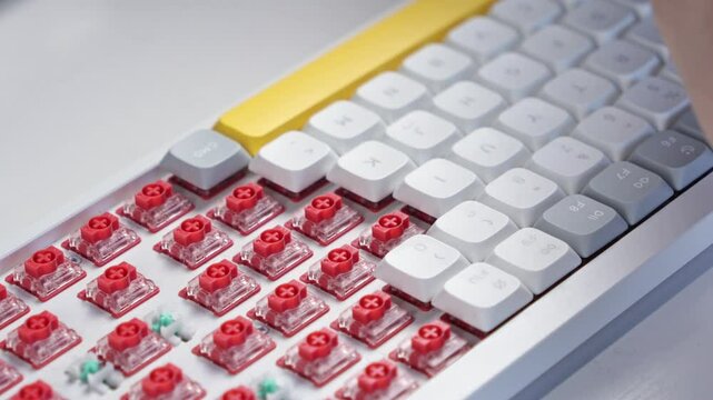 Fingers methodically reinstalling keycaps onto red switches during keyboard reassembly process