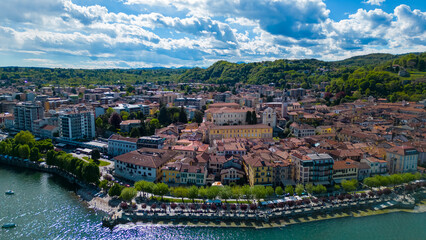 Obraz premium Arona, Lake Maggiore, Italy: A stunning panoramic view of a vibrant city nestled along the serene shores of a picturesque lake, showcasing the harmonious blend of architecture, nature.