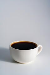 White ceramic cup filled with black coffee on white background