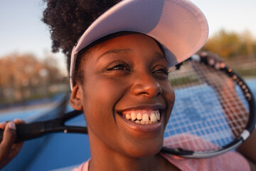 Fototapeta premium Tennis player smiling and holding racket on court