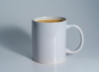White ceramic mug filled with coffee on light background