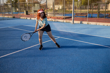 Female tennis player preparing to hit ball on blue court