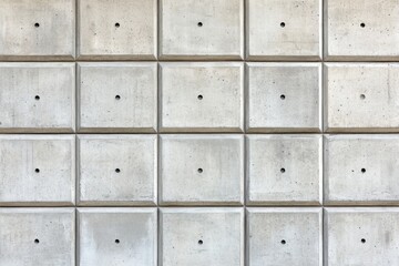 Light gray concrete wall paneling with evenly spaced square tiles and small holes