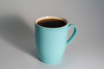 Blue ceramic mug filled with black coffee on neutral background