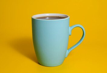 Tall blue ceramic coffee mug on yellow background