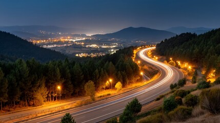 Winding mountain road at night, with city lights in the valley, a scenic landscape view.  Possible use Stock photo for travel, scenic beauty, night driving, road trips
