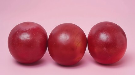 Three ripe plums lined against a pastel pink background for product mockup