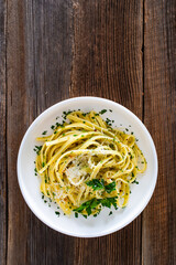Pasta with garlic, parsley and parmesan cheese on wooden table. Spaghetti aglio olio on wooden background