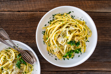Pasta with garlic, parsley and parmesan cheese on wooden table. Spaghetti aglio olio on wooden...